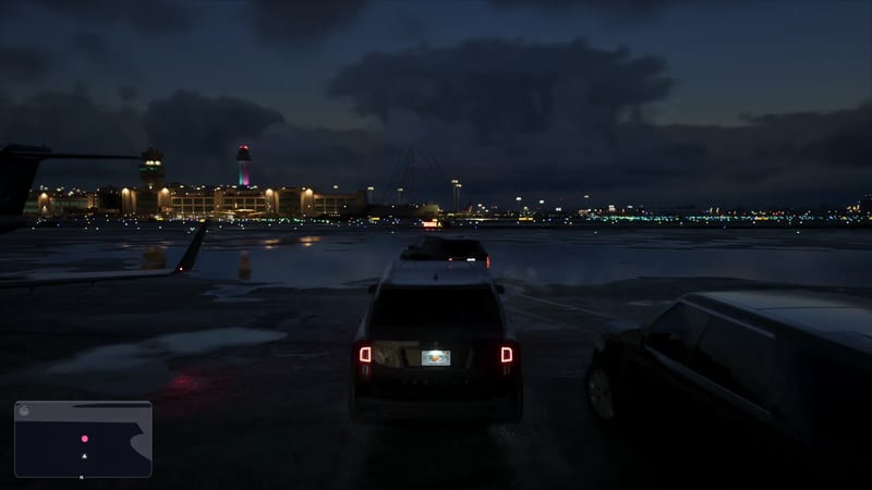 A dark SUV with lit tail lights is parked on a wet airport apron at night, facing distant terminal buildings and control towers under a cloudy sky.
