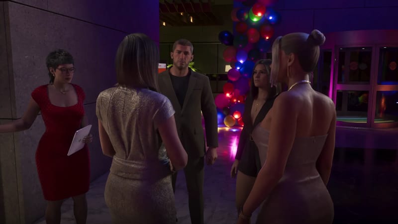 A man in a dark suit faces four women in party dresses in a dim lobby decorated with colourful glowing balloons, with a revolving door behind.