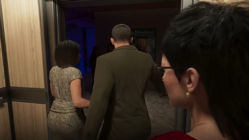 A man in an olive jacket and a woman in a patterned dress walk out of a wood-panelled lift as a woman in glasses looks on, towards a blue-lit lobby.