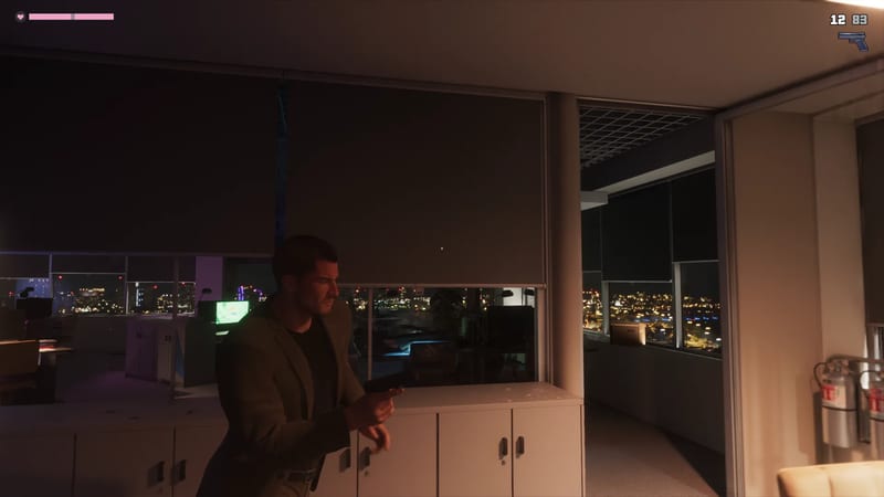 Jason Duval, in a dark olive jacket, moves through a dim office holding a pistol, with city lights glowing beyond the blinds at night.