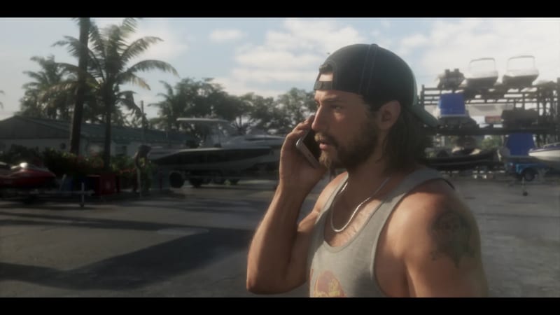 Jason Duval, in a backwards cap and grey vest, takes a phone call in the yard of Brian's Boat Works & Marina on a bright day.