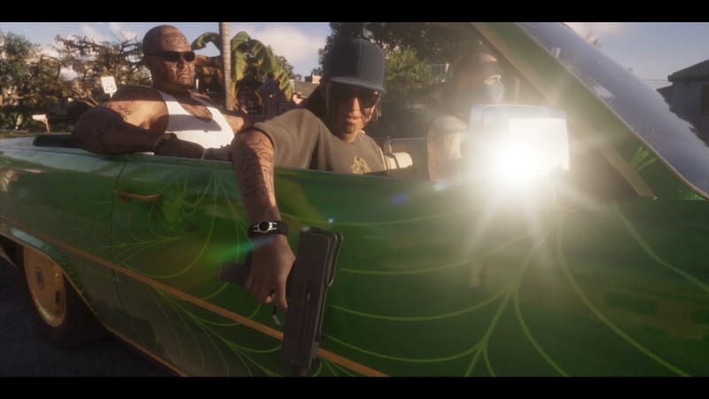 Three tattooed men ride in a green lowrider convertible on a sunny street, one in a cap and sunglasses pointing a compact submachine gun out of the car.