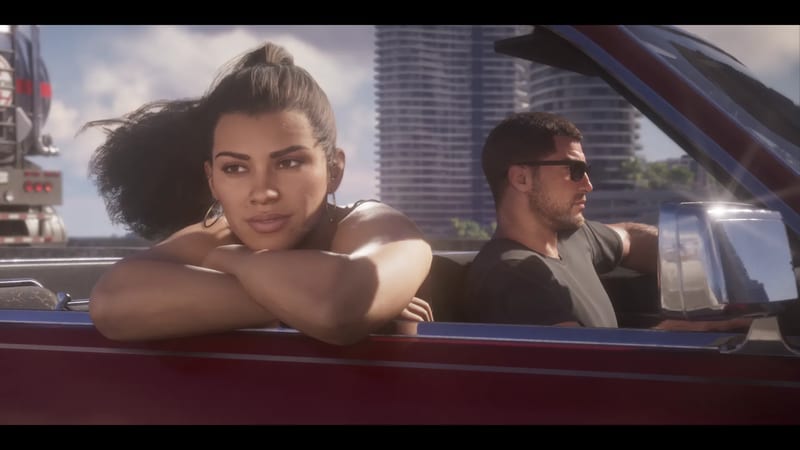 Lucia Caminos rests her arms on the door of a dark red convertible while Jason Duval drives beside her, with tall towers behind in daylight.