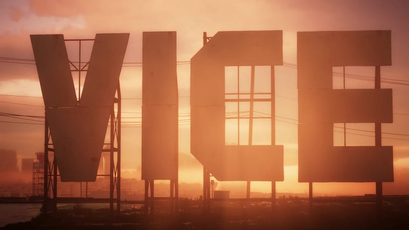 Large weathered letters spelling VICE stand on metal frames, silhouetted against a hazy orange sunset with a distant city skyline.