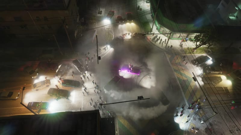 A crowd gathers at a night-time crossroads around a purple-lit car doing a burnout in thick smoke, with a woman standing on its roof, seen from above.
