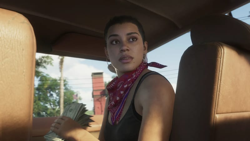Lucia Caminos sits in a vehicle with a red paisley bandana, holding a fan of dollar bills and looking over her shoulder on a sunny day.