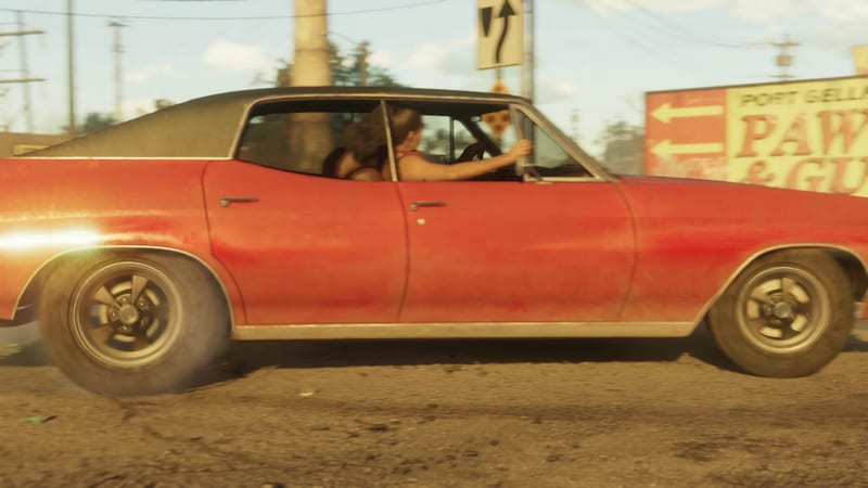 A dusty red two-door car with a dark roof drives past a Port Gellhorn Pawn & Gun sign, a woman at the wheel, on a sunny street.