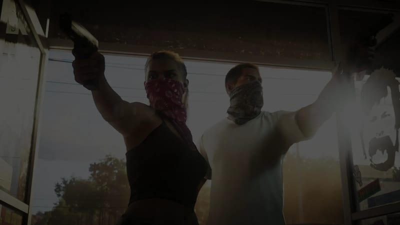 Lucia Caminos and Jason Duval, faces covered by bandanas, aim handguns upwards inside a shop doorway with trees outside.