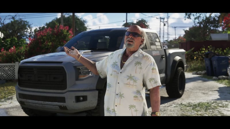 Brian Heder, an older man in sunglasses and a palm-print shirt, gestures beside a grey Vapid pickup truck on a sunny residential street.