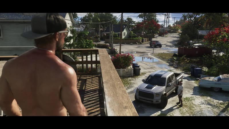 A shirtless man in a cap and sunglasses looks down from a wooden balcony at a silver pickup truck and a man in a white shirt on a sunny residential street.