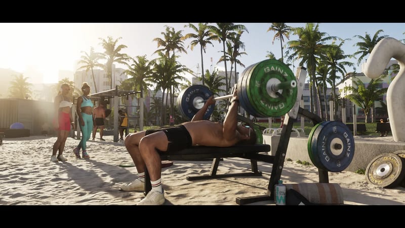 A shirtless man bench-presses a loaded barbell on an outdoor beach gym in Vice City, with palm trees behind and two women watching.