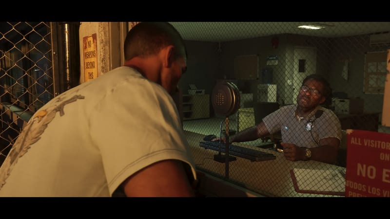 A man in a pale t-shirt leans towards a uniformed guard behind a wire-mesh window in a dim, greenish security office.