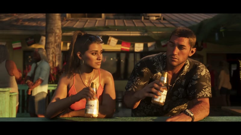 Lucia Caminos and Jason Duval lean on a green bar holding beer bottles at a beachside bar in warm evening light.
