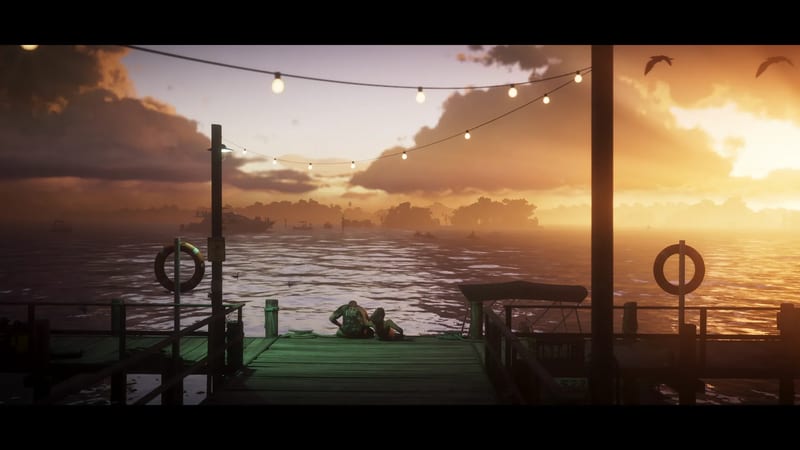 Two people sit close together at the end of a wooden jetty, looking out over open water at a glowing orange sunset, with string lights overhead.