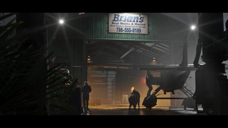 Silhouetted people work around a seaplane outside Brian's Boat Works & Marina, a green shed with a lit sign, at night in damp, misty weather.