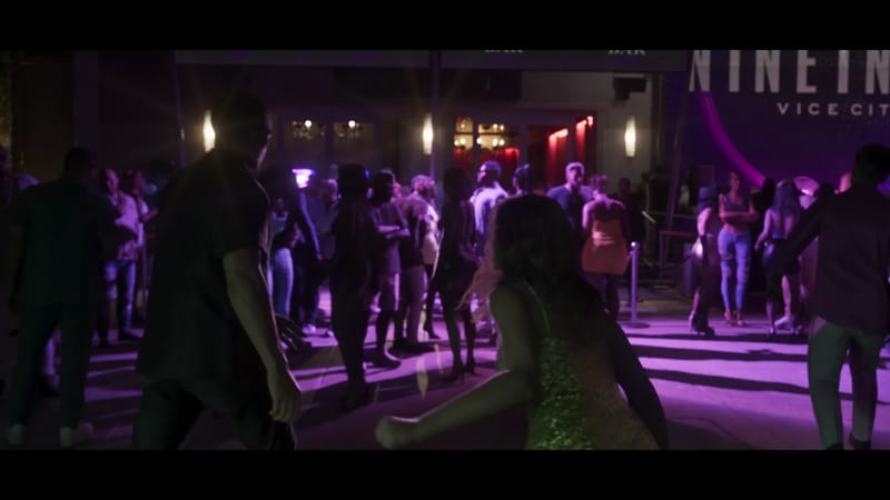 A crowd dances outside a night spot lit in purple, with a woman in a sparkly green dress in the foreground and a sign reading "VICE CITY" above.