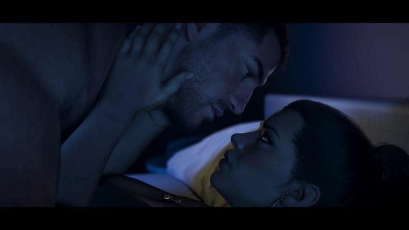 Jason Duval leans over Lucia Caminos in bed, her hand on his cheek, in dim blue light.