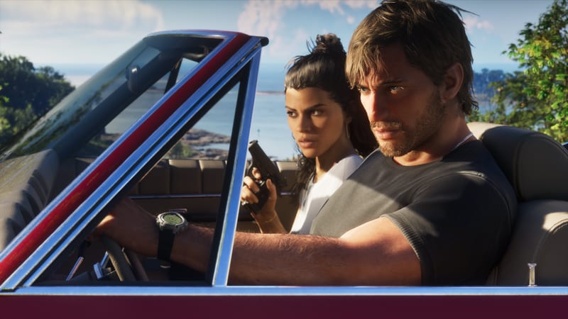 Jason Duval drives a convertible with Lucia Caminos beside him holding a pistol, on a sunny coastal road with the sea behind them.