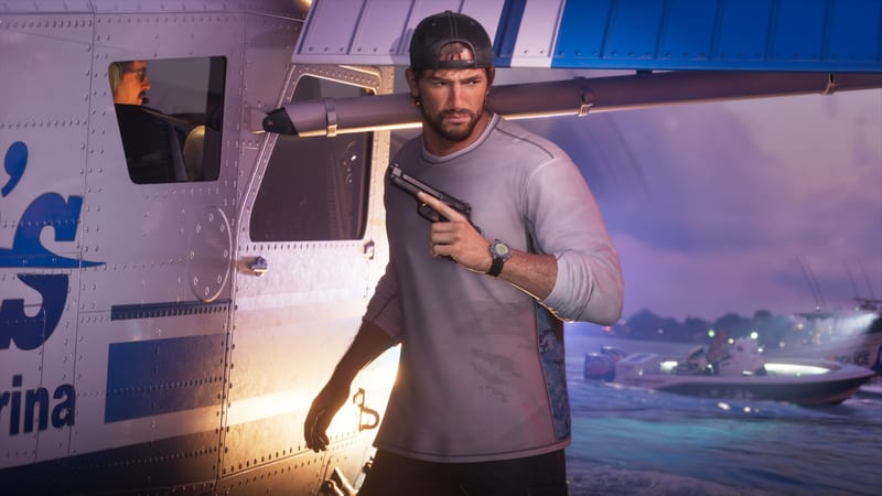 Jason Duval, in a backwards cap, holds a pistol beside a white and blue seaplane at dusk, with a police boat on the water behind him.