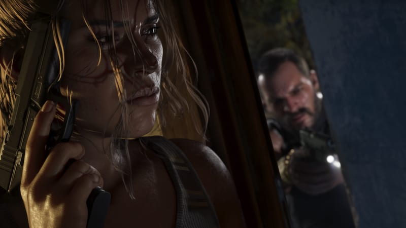 Lucia Caminos holds a pistol beside her face as she peers round a corner, while a blurred man aims a gun at her from behind.