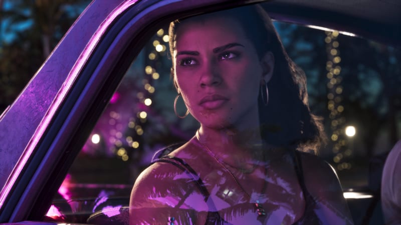 Lucia Caminos looks out through a car window at night, lit in pink and purple, with strings of fairy lights behind her.