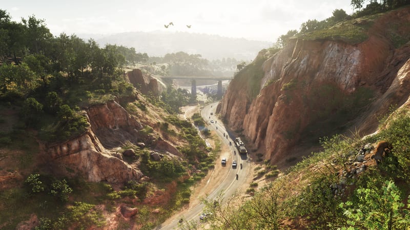 A winding road runs through a red-walled gorge in Mount Kalaga, with a tanker lorry, cars and motorbikes below a distant bridge and birds overhead.