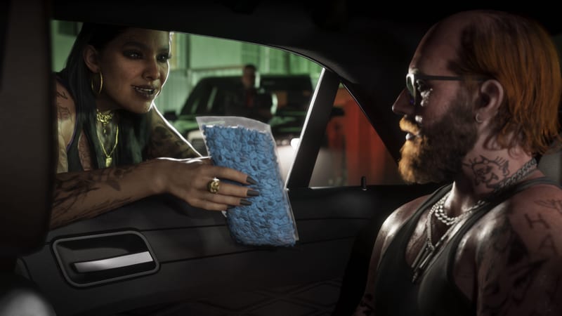 A tattooed woman leans in at a car window holding a large clear bag of blue pills towards a bearded, red-haired man in sunglasses inside the car.