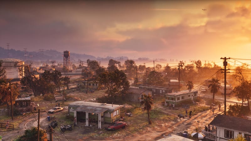 A trailer park with green and white mobile homes, quad bikes and a red car under a golden sunset sky, in Port Gellhorn.