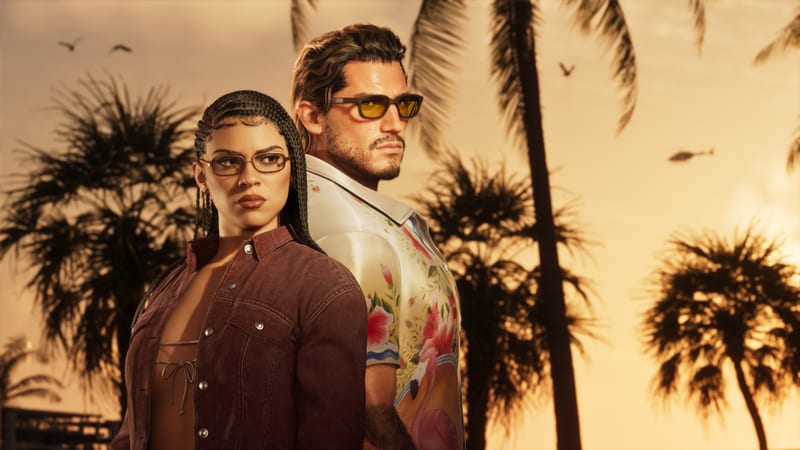 Lucia Caminos and Jason Duval stand back to back among silhouetted palm trees at sunset, he in a floral shirt and yellow sunglasses, she in a maroon jacket.