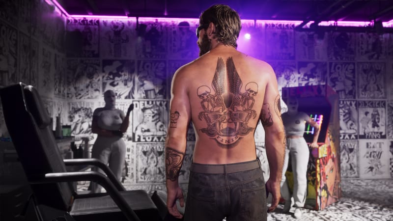 Jason Duval stands shirtless with his back to us, a winged skeleton tattoo across his back, in a tattoo studio lit with purple neon.