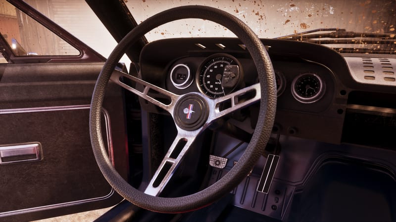 Close view of the steering wheel and dashboard inside a '67 Vapid Dominator Buggy, with the driver's door open and mud flecked on the windscreen.