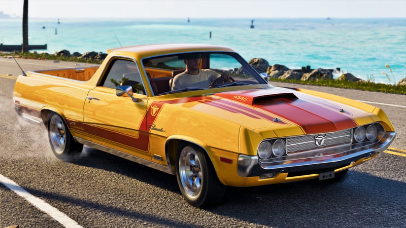 A man drives a yellow Vapid Ganado pickup truck in GTA 6 with red bonnet stripes along a coastal road beside turquoise sea on a sunny day.