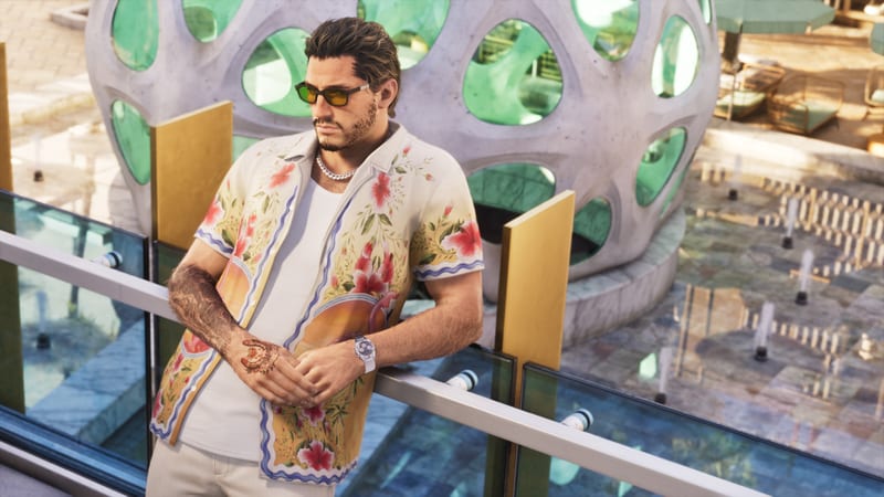 Jason Duval leans on a glass and steel balcony rail in a floral shirt and yellow-lensed sunglasses, above a plaza with fountains and a lattice dome.