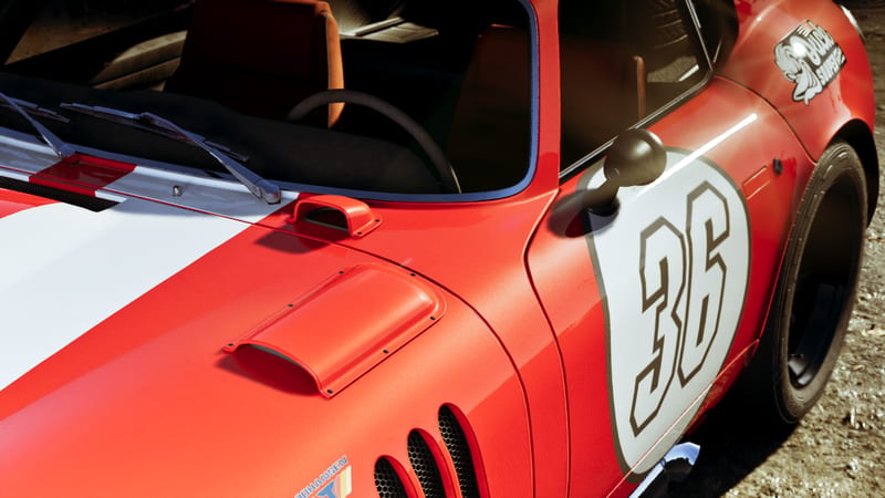 Close-up of a red classic sports car with a white racing stripe, a white roundel with the number 36 on the door, and bonnet vents, parked on gravel.