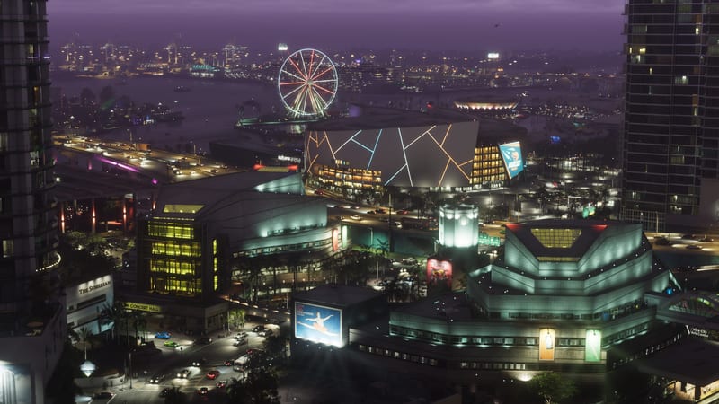 Sahara Arena and a lit Ferris wheel beside a busy highway and waterfront in Downtown Vice City at night, seen from above.