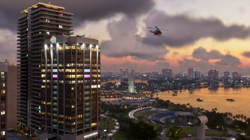 A helicopter flies over a waterfront park and Ferris wheel in Vice City at dusk, beside a lit tower with a Megamundo sign.