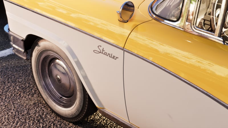 Close-up of the front wing and wheel of a yellow and white '55 Vapid Stanier with chrome trim, parked on dark tarmac in warm light